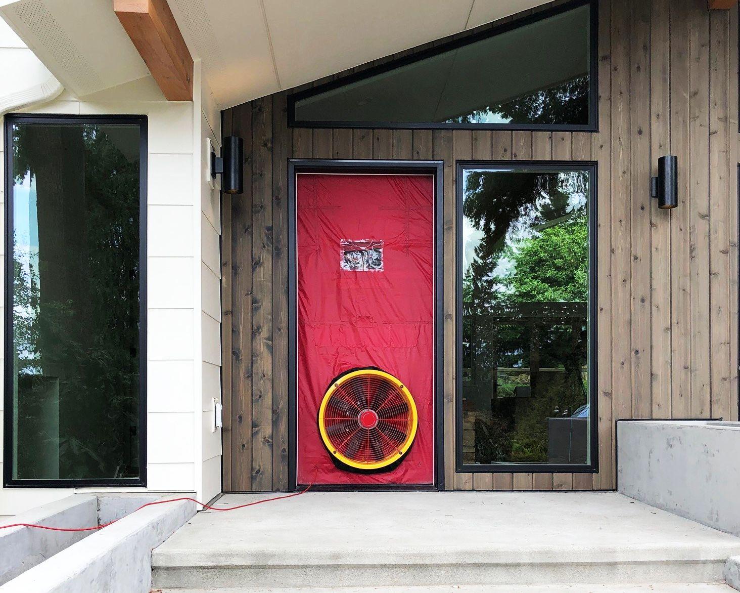 Front door of a house with a red blower door test set up for energy efficiency inspection.