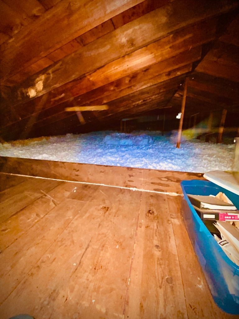 Project Probono LLC installing blown attic insulation in the Lehigh Valley — technician applying fiberglass to reach R-49, with storage damming for full thermal coverage.