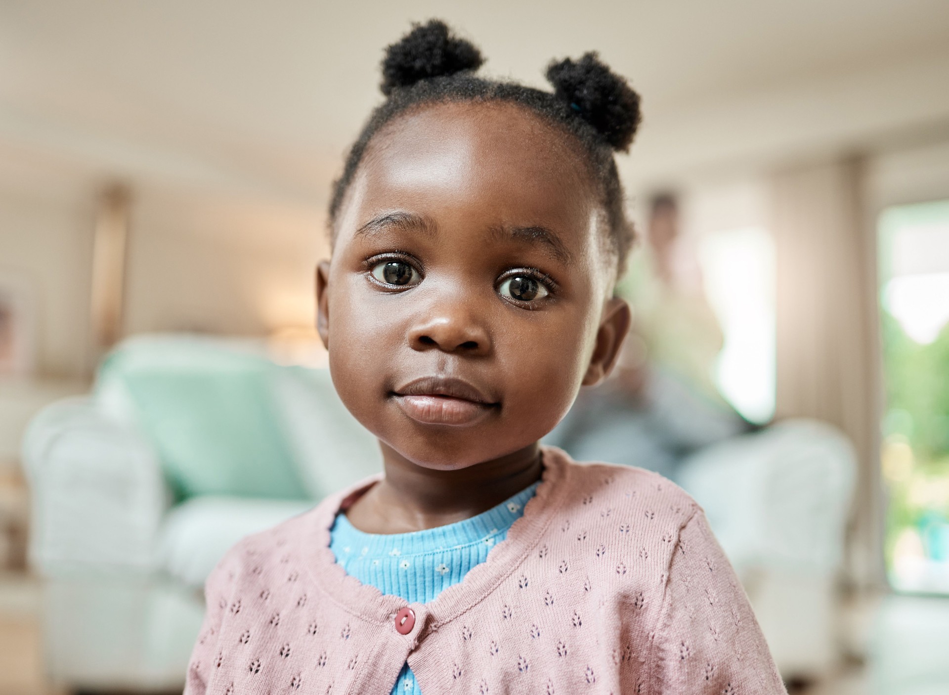 Cropped portrait of an adorable little girl with pigtails sitting on the living room floor at home